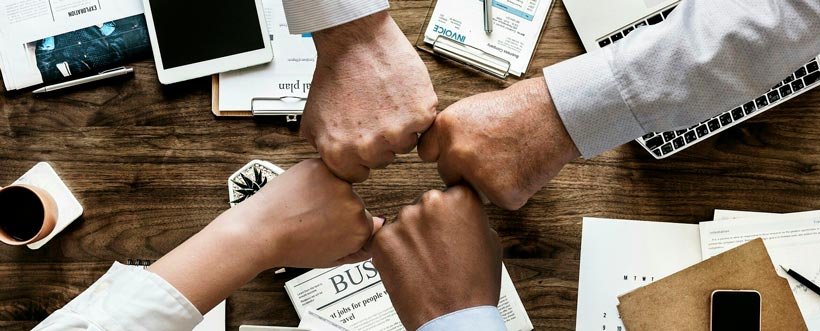Varios puños unidos sobre la mesa simbolizan el compromiso del equipo con la transparencia empresarial